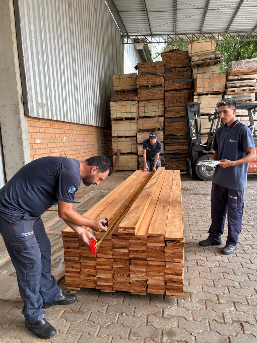 Marine Box inspectors measuring and documenting hardwood boards before loading